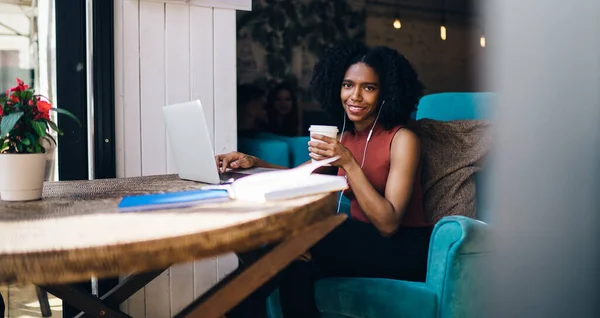 夏の屋外テラスカフェで青い椅子に座ってノートパソコンでサーフィンカジュアル服の現在の髪の民族の女性 — ストック写真