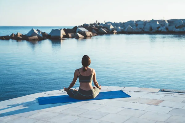 Bakåt Bild Dam Yogakläder Sitter Blå Matta Lotusposition Stenpiren Morgonen — Stockfoto