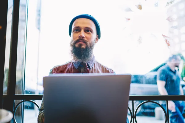 Ernsthafter Bärtiger Hipster Lässigem Outfit Der Laptop Schmökert Und Wegschaut — Stockfoto