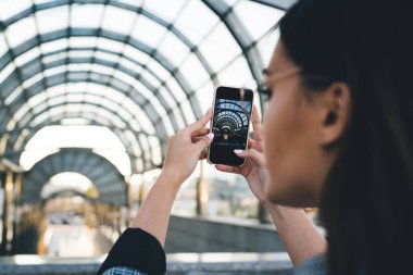 Gezgin kadın gezgin elinde taşınabilir prote ile blog paylaşımı için kentsel ayarların fotoğrafını çekiyor, çağdaş şehir mimarisinin fotoğrafını çekiyor akıllı telefon kamerasıyla.