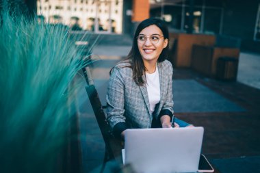 Neşeli Kafkasyalı serbest çalışan, dizüstü bilgisayarda çalışmak için güncelleme yazılımını görmezden gelen açık havada bankta oturan, sosyal ağlarda binlerce yıllık yenilikçi kız blogu medyayı paylaşıyor.