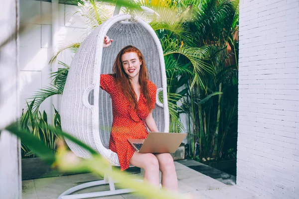 Genç Kızıl Saçlı Dizüstü Bilgisayarı Olan Benekli Elbiseli Asılı Sandalyeye — Stok fotoğraf