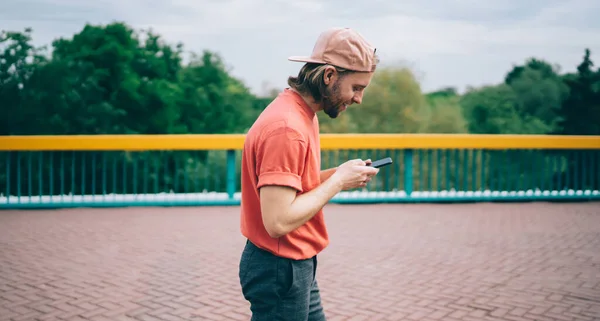 Smiling Bearded Young Man Casual Clothes Cap Using Mobile Chatting — Stok Foto