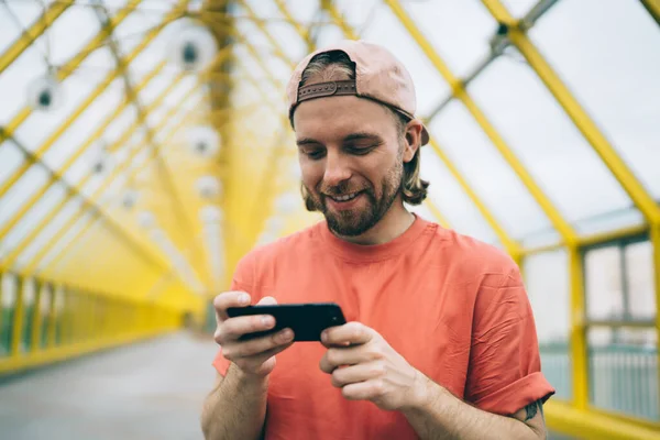 평상복 차림의 남성이 보행자용 다리에서 비디오를 핸드폰을 사용하는 화면을 행복하게 — 스톡 사진