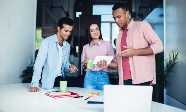 İş molası sırasında online taramadan ve modern dijital tablet üzerinde ağ kurmaktan keyif alan neşeli çeşitli meslektaşlar iş projesi hakkında beyin fırtınası, iletişim teknolojisi kavramı