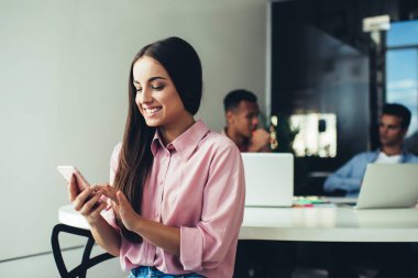 Mesai arasında sosyal ağlarda sörf yaptığı için ofiste 4G 'ye bağlanan mutlu beyaz kadın, e-postaları kontrol eden ve mobil iletişimden keyif alan neşeli bayan işveren
