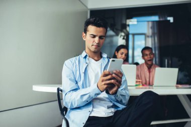 Erkek çalışanın iş günü internet üzerinden para transferi için bankacılık başvurusu yapması, cep telefonu cihazıyla İspanyol yöneticinin kablosuz mesajlaşma sırasında posta kutusunu kontrol etmesi