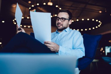 İş günü araştırma sırasında iyi görünümlü bir finans uzmanı tarafından okunan sözleşme fırsatı. Kurumsal stratejinin analizi, resmi giyinmiş beyaz iş adamı, giysi değişimi verimliliği.