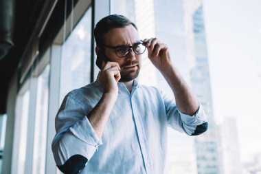 İş günlerinde danışmanlık yapmak için cep telefonu aygıtı kullanan klasik gözlük takan Kafkas işvereni, cep telefonu uygulaması aracılığıyla şaşkın iş adamının ortağına seslenişi