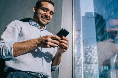 Başarılı erkek işveren akıllı telefon aygıtında iş parası alışverişi yapmak için 4G kablosuz bağlantı kullanarak olumlu e-posta mesajı okuyor, mutlu Kafkas finans uzmanı cep telefonu mesajları gönderiyor