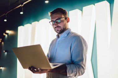 Modern dijital teknolojide internet üzerinden online sermaye analitiği yapmak için şirket wifi internetine bağlanan milenyum pazarlamacısı, gözlüklü beyaz adam