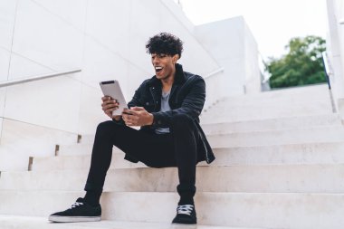 Şaşırmış hipster adam şehir merdivenlerinde dinleniyor haberleri okuyor ve dijital tabletle aldığı e-postaya şaşırıyor kablosuz internete bağlanıyor, modern dokunmatik ped ile mutlu adam ağları ile sohbet ediyor.