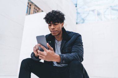 Latin hipster 'ın internet sitesinde akıllı telefon dinlenmesi üzerinden video izlemek için geri bildirim göndermesi, genç adamın arkadaşa cep telefonu uygulaması kullanarak internette sohbet etmesi.