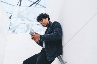 Cep telefonu cihazlı, olumlu gülümseyen adam internet mağazasındaki satışlarla ilgili haberler alıyor. Milenyum hipster 'ı, şehrin arka planında akıllı telefon mesajı ya da yayınını okuyarak ayakta duruyor.