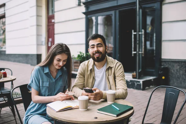 Etniskt Skäggig Man Och Ung Kvinna Ler Och Bläddrar Smartphones — Stockfoto