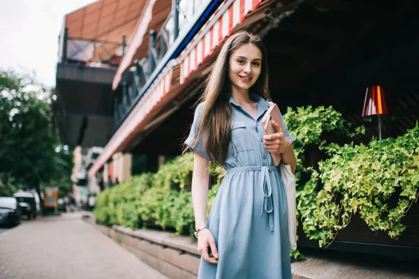 现代成功的女自由撰稿人 手里拿着日记和智能手机 站在咖啡店的阳台旁边 微笑着看着相机 — 图库照片