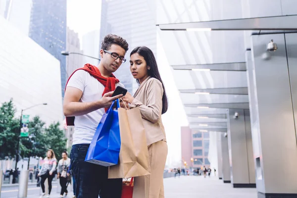 Baixo Ângulo Sério Casal Atento Diverso Roupas Casuais Usando Smartphone — Fotografia de Stock