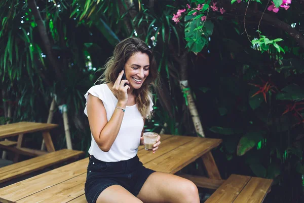 Mulher Relaxada Alegre Sentada Mesa Jardim Madeira Perto Plantas Tropicais — Fotografia de Stock