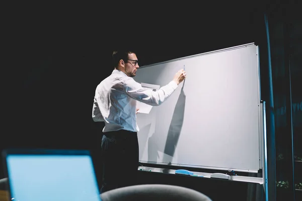 穿着正式服装 戴着眼镜 专心致志的员工 为站在现代办公室舞台上的同事在白板上写信息 — 图库照片