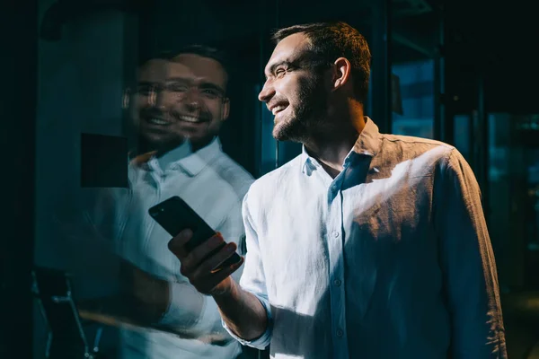 Successful young male executive manager using 4g internet on cellphone technology and laughing, cheerful Caucasian enjoying mobility with smartphone device during work day in office company