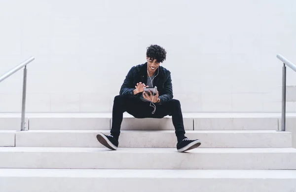 Hombre Joven Afroamericano Sonriendo Sentado Las Escaleras Mientras Envía Mensajes — Foto de Stock