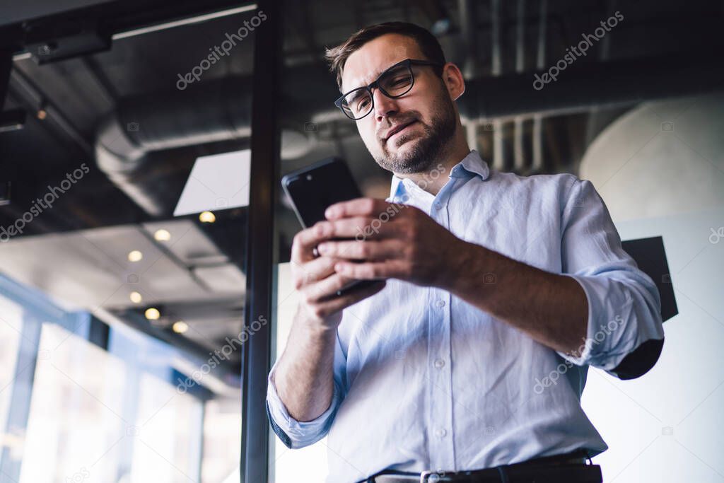 Puzzled business analytic received message from company customer connecting to 4g wireless for mobile chatting, Caucasian man in optical glasses reading financial news during digital marketing