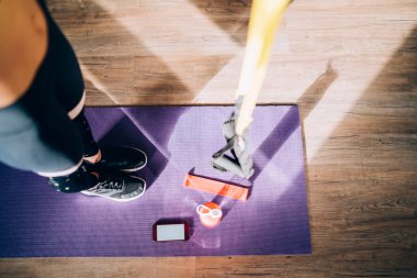 Yukarıdan gelen güçlü sporcuların bacakları simülatör eğitimi için hazır şişe fitness lastiği ve cep telefonu ile mor minderin üzerinde duruyor. 