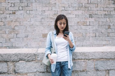 Tuğladan çitlere yaslanan ve elinde beyaz kağıt bardakta kahve tutarken akıllı telefon kullanan gündelik kıyafetlerle etnik kadınları cezbediyor.