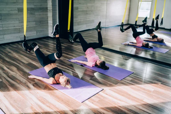 在健身课的演播室训练中 活泼的女士躺在蓝色的体操垫上 并通过抬腿进行锻炼 — 图库照片