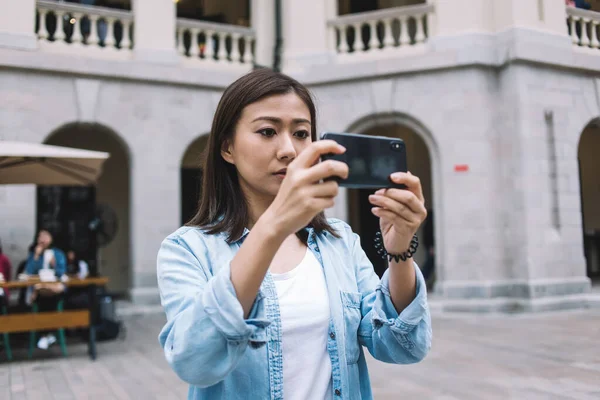 Skupiona Piękna Azjatycka Turystka Niebieskiej Koszuli Robi Zdjęcie Smartfonem Stojąc — Zdjęcie stockowe