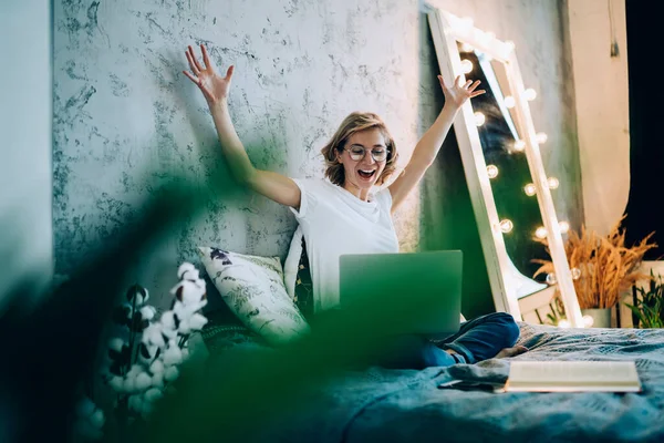 Surprised hipster girl feeling excited from received email message with discounts for shopping in favourite web store, happy amazed woman with expression emotions rejoicing in home apartment