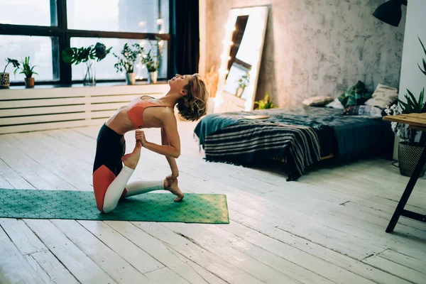 在家里用绿色垫子锻炼身体肌肉时 让嬉皮士女孩平静下来 让她们的腿和背都平静下来 这是很有吸引力的女运动员在做伸展柔韧的运动 — 图库照片
