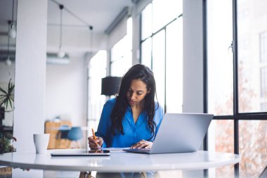 Düşünceli esmer Afrikalı Amerikalı iş danışmanı laptopta çalışırken ve Cafe 'de beyaz yuvarlak masada otururken bilgi yazıyor.