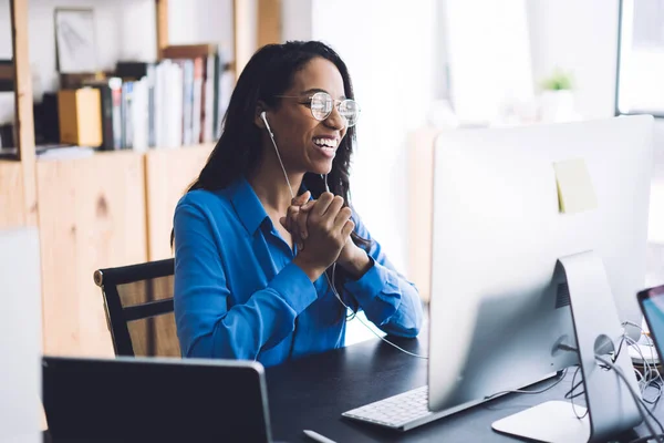 Onnellinen Nuori Afroamerikkalainen Naispuolinen Toimistotyöntekijä Sinisessä Paidassa Laseissa Istuu Työpöydässä — kuvapankkivalokuva
