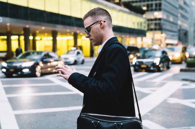 Ciddi ve odaklanmış bir erkek işçinin yol kenarında duran ve sosyal medyada bulanık arka planda sohbet eden