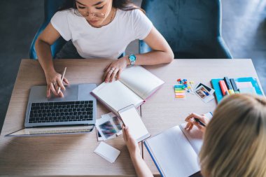 Yoğunlaştırılmış, dizüstü bilgisayarlı, not defterleriyle dolu renkli çıkartmalarla dolu masada oturan modern işyerindeki akıllı telefonlardan.