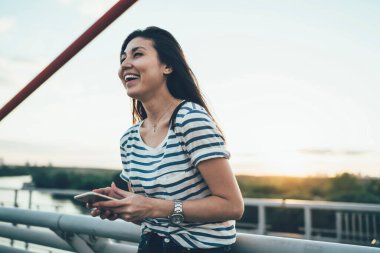 Mutlu Asyalı kadın gezgin, gezintiden çok memnun. Gezgin bağlantı yoluyla arkadaşına mesaj gönderiyor. Neşeli hippi kız turist blogcusu sosyal medyadan eğleniyor.