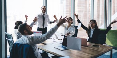 Modern ofisteki meslektaşları ve liderleriyle masaya otururken heyecanlı iş adamlarının belgeleri attığı bir şirket.