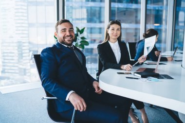 Megapolis 'teki modern ofiste dizüstü bilgisayar kullanırken rahat ofis sandalyelerinde oturup kontrat imzalayan ve kameraya bakan takım elbiseli sevgili meslektaşlarım.