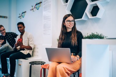 Optik gözlüklü çekici bir bayan grafik tasarımcısı gülümserken, modern dizüstü bilgisayarda uzaktan iş ararken, dijital programlama teknolojisi olan mutlu hippi kız.