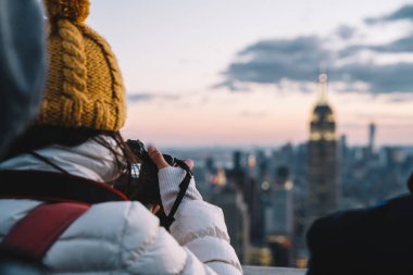 Kış kıyafetleriyle gezginlerin gece vakti gökdelenlerin fotoğrafını çekerken New York 'u gezerken görüntüsü. Görülmeye değer Empire State Binası Tarihi Eser 