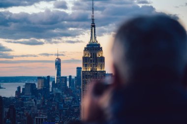 Gece vakti gökdelenlerin fotoğrafını çeken erkek gezginin New York 'u keşfederken görüntüsü. Ünlü Empire State Binası 'nı gezmek. Sahne şehir manzarası