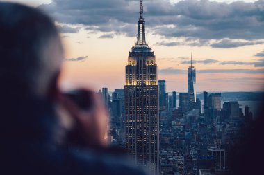 Gece vakti gökdelenlerin fotoğrafını çeken erkek gezginin New York 'u keşfederken görüntüsü. Ünlü Empire State Binası 'nı gezmek. Sahne şehir manzarası