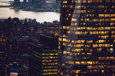 Manhattan 'ın çeşitli yüksek gökdelenlerinin gökdelenlerinin gökdelenleri. New York' ta akşam saatlerinde pencereleri açık olan binalar. Metropolis 'in gece hayatı, ofisler ve gayrimenkul. Şehir merkezindeki yapılar