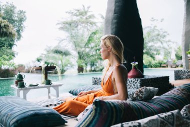 Bali 'de havuz kenarında dinlenirken hayatı düşünen ve tatilin tadını çıkaran düşünceli, özgür, sakin bir kadın.