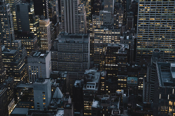 Aerial view of various high Manhattan buildings and skyscrapers with lighted windows located in New York city at evening time
