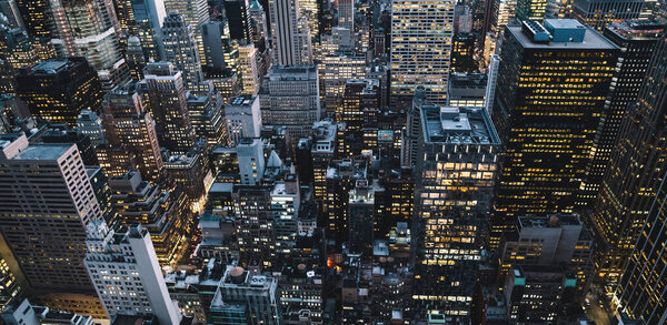 Aerial view of various high Manhattan structures and skyscrapers with lighted windows located in New York city at evening time