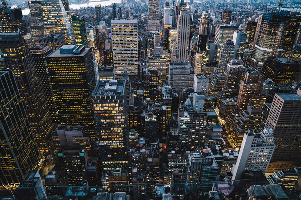 Aerial view of skyscrapers and towers in midtown skyline of Manhattan with evening sunset sky. Scenery cityscape of financial district with famous New York Landmark, illuminated Empire State Building