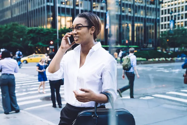 现代自信的非洲裔美国女人 穿着正式的白衬衫 戴着眼镜 站在市中心的城市街道上用智能手机交谈 — 图库照片