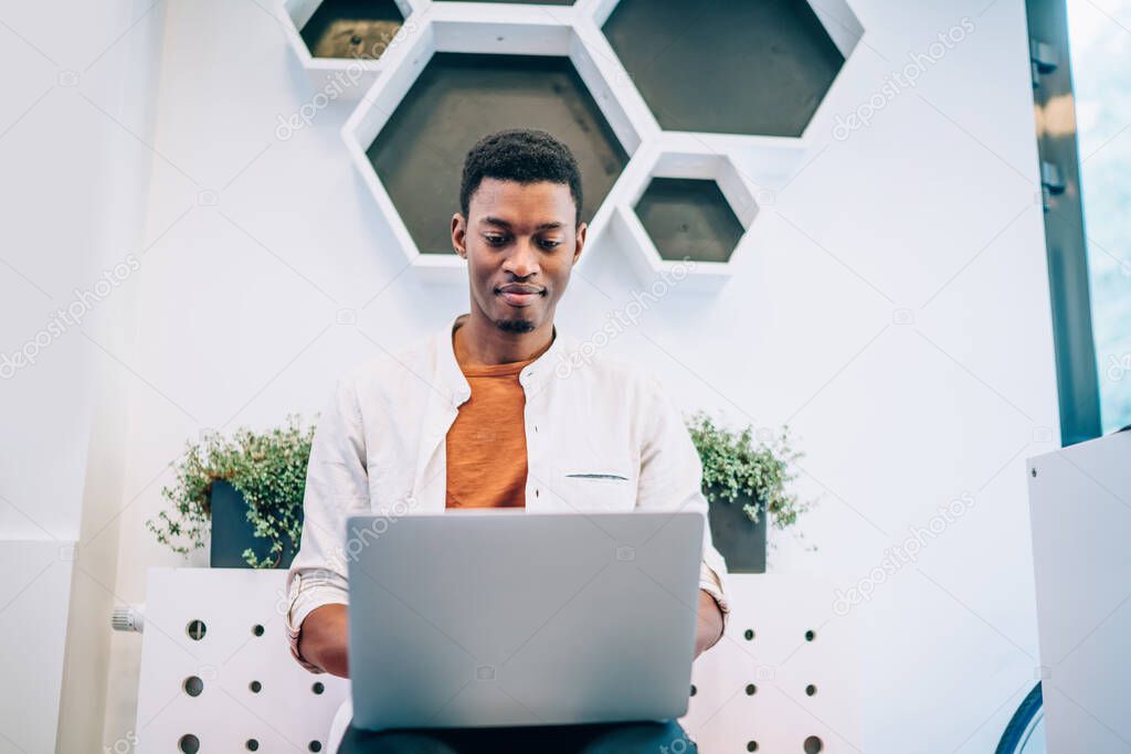 Skilled male programmer with dark skin developing web platform for IT professionals using 4g wireless internet on modern laptop computer, African American man communicate in social medial networks